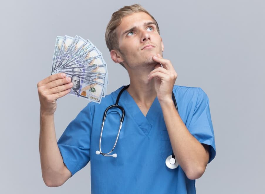 A contemplative male nurse holds a fan of cash bills