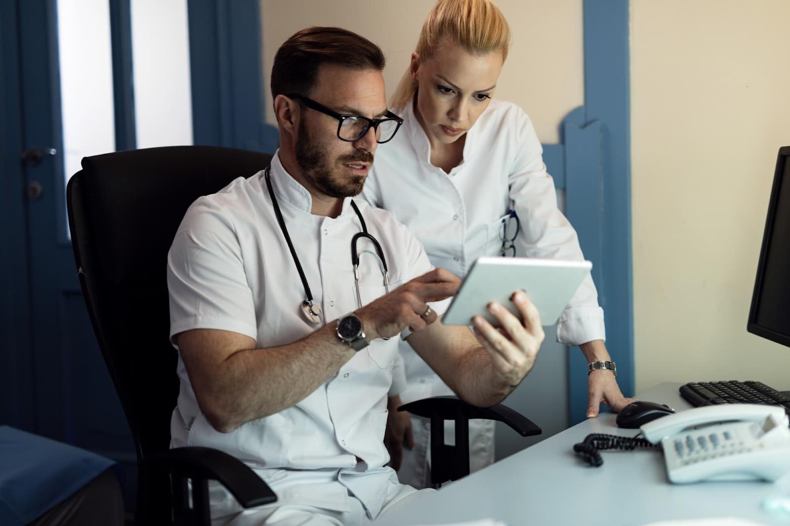 A male doctor and a nurse are looking at something on a tablet