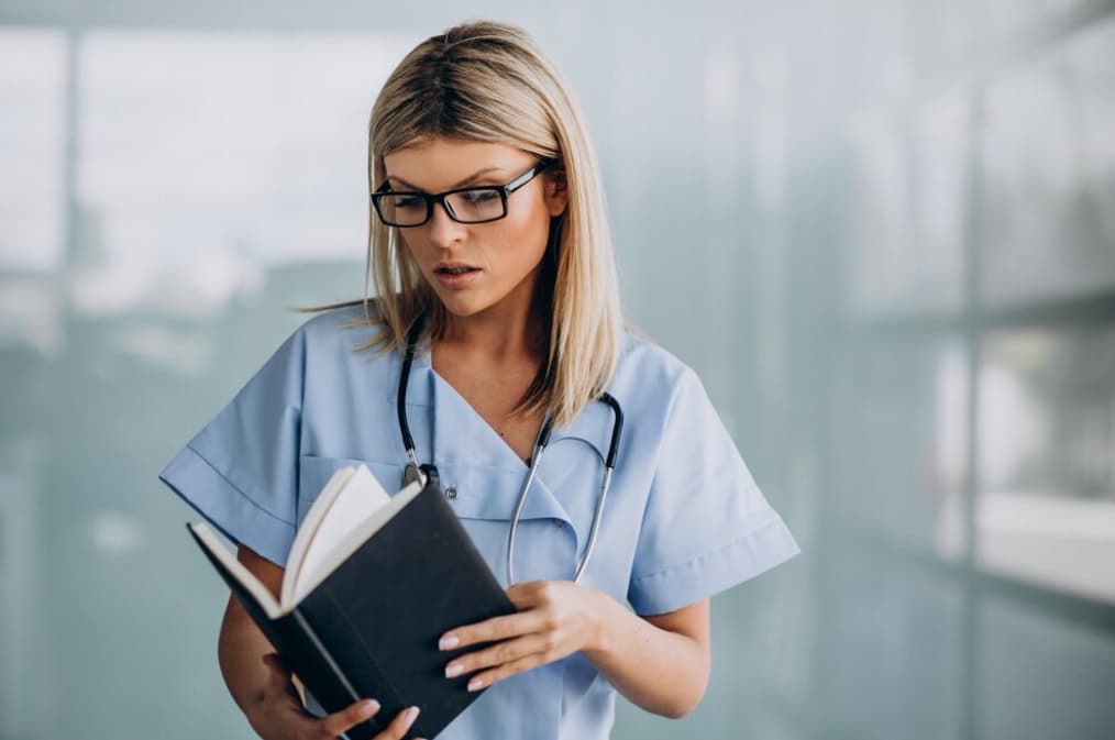 A serious female nurse reading a book with intent