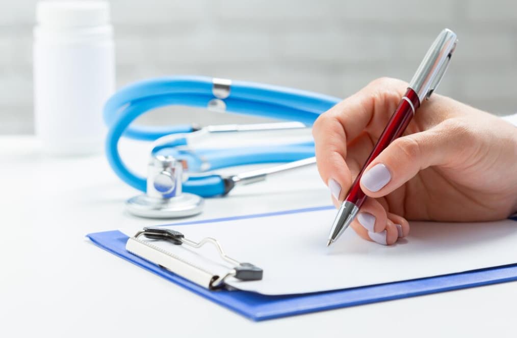 Close-up view of a hand writing on a medical chart