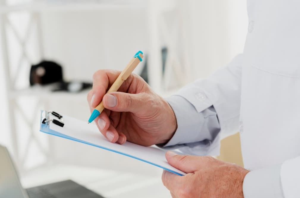 A close-up of a person's hands holding a pen over a clipboard