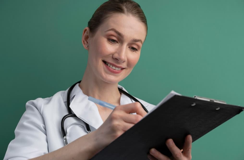 A smiling female doctor writes on a clipboard