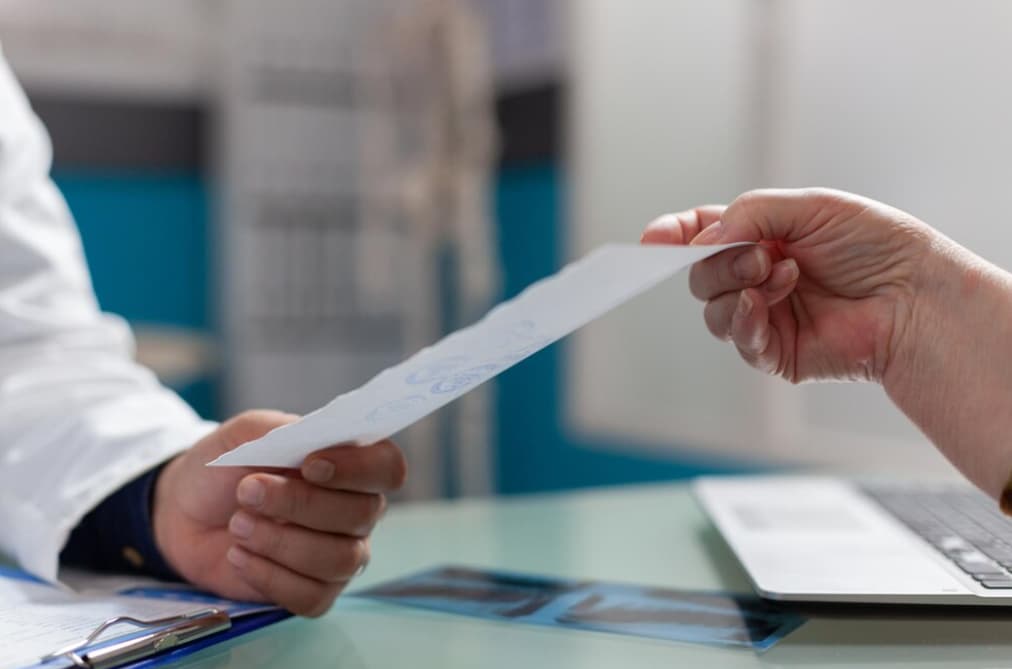 A doctor hands over a document to a patient